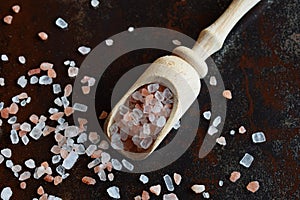 Coarse pink salt in wooden spoon on black background. Himalayan Salt. Copy space