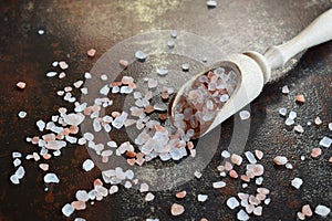 Coarse pink salt in wooden spoon on black background. Himalayan Salt. Copy space