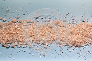 Coarse rock pink sea salt on blue background