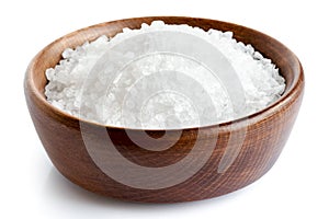 Coarse salt in wooden dish on white.