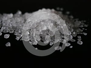 Coarse sea salt crystals isolated on black background close up