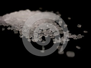 Coarse sea salt crystals isolated on black background close up