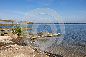 Coast Dutch lake IJmeer near Muiden with fence and stones