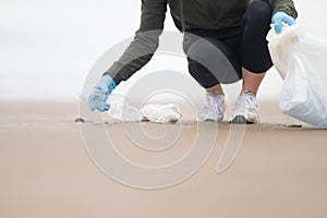 Coast. Environmental protection. A volunteer collects garbage and plastic waste in a bag on the ocean shore. Involvement in the