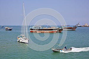 Coast Guard boat goes by luxury sailing boat, fishing and cargo ships