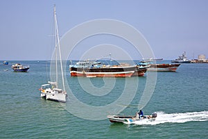 Coast Guard boat goes by luxury sailing boat, fishing and cargo ships