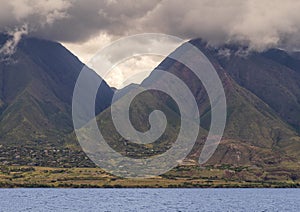 Coast of Maui with lava mountains topped by clouds photographed from Lahaina Bay.