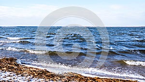 Coast of Minsk Sea, Belarus. Coastal landscape with sandy beach and rough sea on winter sunny day