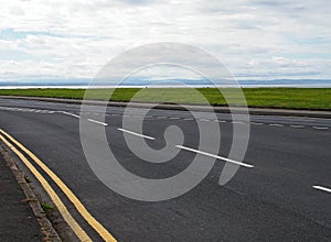 Coast road at crosby in merseyside with grass surrounding the sea at the mouth of the river mersey