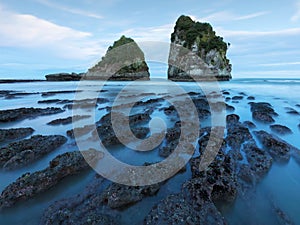 Coast sea. Sunset. Wild rock beach. The natural rock formation. Red sun over summer sea. Cloud on a blue sky over summer sea.