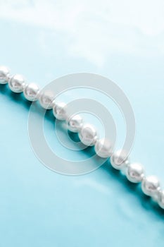 Coastal jewellery fashion, pearl necklace under blue water background, glamour style present and chic gift for luxury jewelery