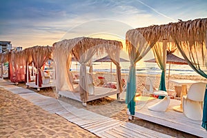 Coastal landscape at sunrise - view of the sandy seashore with beach gazebos