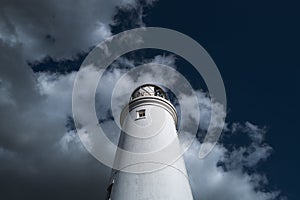 Coastal lighthouse seen rising above the roofs of terraced houses.