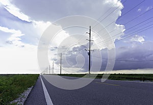 On the coastal prairie, utility poles, lines and pavement converge at the vanishing point