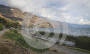 Coastal road along lake Atitlan with pier along mountainrange at Panajachel, Guatemala