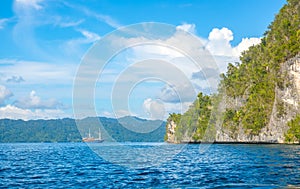 Coastal Rock With Rainforests and Yacht in the Distance