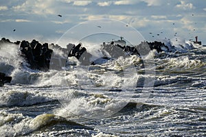 Coastal storm in the Baltic Sea, big waves crash against the harbor breakwater, breaking wave