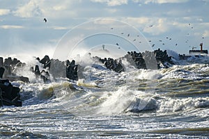 Coastal storm in the Baltic Sea, big waves crash against the harbor breakwater, breaking wave