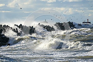 Coastal storm in the Baltic Sea, big waves crash against the harbor breakwater, breaking wave