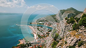 Coastal town Omis with mountain river and marina shelter boats on the background. Red rooftops contrast with azure sea