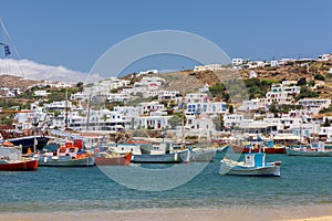 Coastal view of the Greek island of Mykonos, with whitewashed homes and fishing boats anchored in the harbor.