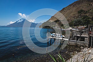 Coastal view with jetty along the village on lake Atitlan with view on volcano peak in Santa Cruz la Laguna, Guatemala