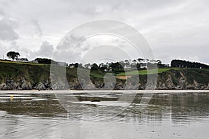 Coastal view with reflection of houses on beach at low tide