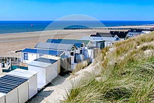 Coastal view with vacation homes, dunes, empty beach, blue sea and clear sky.