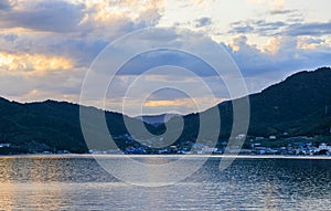 Coastal village by calm water and mountains on Shodo Island at sunset photo
