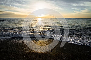 Coastal waves at sunset. Colorful sunset on a sea beach.