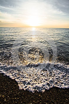 Coastal waves at sunset. Colorful sunset on a sea beach.