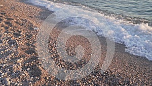 Coastline close up. Sea waves washing ashore in slow motion. Pebbles beach at sundown sunrise time. Adriatic sea in