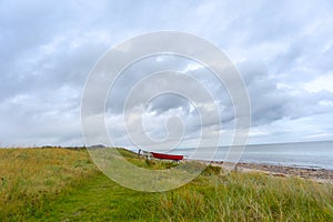 a coastline at the East Sea in Denmark with asmall red boat