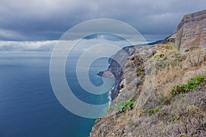 Coastline of Madeira with high cliffs along the Atlantic Ocean. Dramatic sky