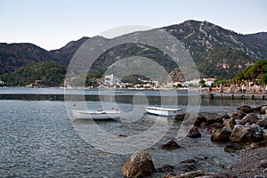 Coastline in resort village in morning. Two white boats in the sea water at sunrise. Calm seascape of sun rising over