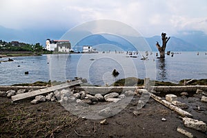 Coastline view at lake Atitlan with dead tree, house and mountainrange, San Pedro de la laguna, Guatemala photo