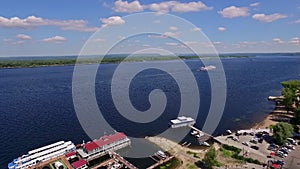 coastline of wide river with boat dock, aerial view at summer, big motorship is moving on central of river