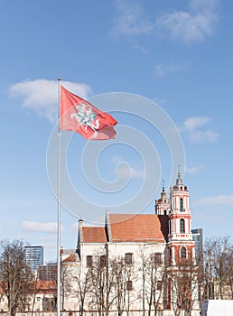 Coat of arms of Lithuania flag. Knight on horse with sword and shield on red background. Blue sky with clouds and church