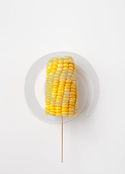 The cob boiled corn on a stick on white background