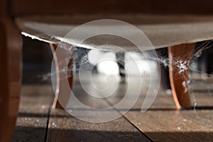 Cob webs under an antique chair on wooden flooring