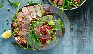 Cobb salad bowl with grilled chicken breast, asparagus, avocado, radishes and bacon