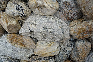 Cobble of gneiss metamorphic stones on the rock wall.