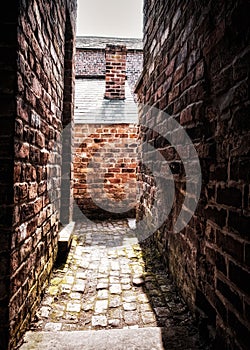 Cobbled passageway between historic red brick cottage walls
