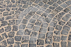 Cobbled road close-up. Pedestrian paving in street. Paved, detail. Brown texture of a paving stone track on sand