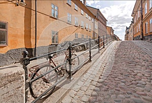 Cobbled stones of of street with city bicycle parked between colorful historical houses. Old area of Stockholm, Sweden.