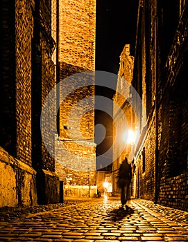 Cobbled street of Old Town with dark blurred silhouette of person. Evokes Jack the Ripper