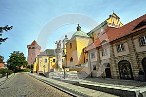 cobbled street with a statue of lancer and a historic church and a tower of a medieval castle photo