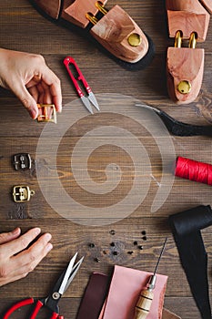 Cobbler with tools work process dark background top view