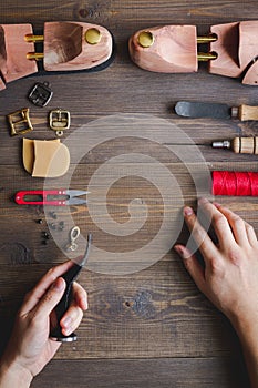 Cobbler with tools work process dark background top view