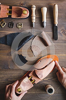 Cobbler with tools work process dark background top view